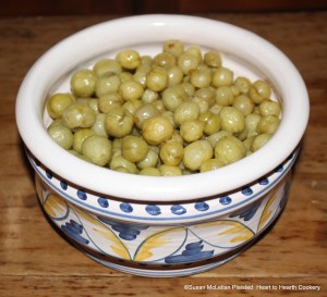 A gally pot of gooseberries preserved in white wine and sugar, drained of their syrup and ready for the receipt (recipe) "To bake preserved Gooseberries in pie"