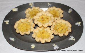 The receipt (recipe) "To make Orange Cheese Cakes" was prepared with the peel of three Seville oranges, six ounces of loaf sugar, half a pound of butter, four eggs and a spoonful of orange-flower water.  Pictured are the baked orange cheese cakes presented to table and garnished with candied Heart's ease.
