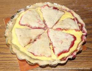 After the baking of the cream, egg yolk and sugar mixture for the receipt (recipe) To make a Rasberry Tart, let it stand till it is cold and the cut Puff-paste lid is laid on the cooled tart.  The first baking was a layer of fresh raspberries strewed with sugar now covered with the custard and paste.