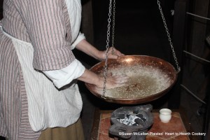 The first layer of sugar is added to the caraway seeds for the receipt (receipt) Caraway Comfits by using one flat hand moving the seeds quickly through the syrup and around the pan while the other hand swings the comfit pan so it is not directly over the heat from the brazier all the time.