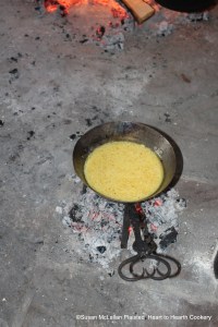 After the whisked eggs have been mixed with sugar, vinegar and water for the Pennsylvania German Heesse Schpecksass (Hot Bacon Sauce), the mixture is thickened in a spider greased with bacon fat over a burner of embers until a sauce.