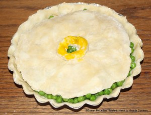 After the peas have been seasoned with salt, saffron, butter and sugar for the receipt (recipe) Green Peas Tart close it.  The tart is closed with another piece of fine, cold paste (pie crust) with a decorated hole in the center for the addition of verjuice after the tart is baked.