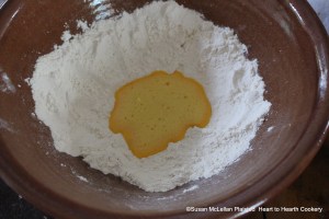 After two eggs have been whisked very well for the receipt (recipe) Maccaroni, a half pound of flour was weighed on my balance scales. I then lined my bowl with the flour and added the bubbly whisked eggs.