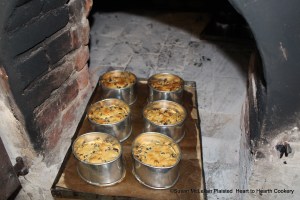 The greased, brown paper lined tin baking sheets with individual cake hoops containing the receipt (recipe) A Pretty Cake were removed from the bake oven when done piping hot.