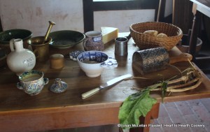 The table is ready with the ingredients for the next 17th century receipt (recipe), A made dish of Parmizant. Note the horse radish in the lower right of the table, small manchets (bread) in the rye straw basket, wedge of Parmesan cheese to the left of the basket, and caraway comfits in the blue and white porringer in the center. Only the tarragon is missing from view.