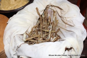 The skirrets for the receipt (recipe) Skittet Fritters were placed in a pudding bag to boil until very tender.  Using a pudding bag in a boiling cast iron pot of water makes retrieving all the skirrets with the removal of the bag and results in whole roots.  The tender white flesh of the skirret and the loosened peel is pictured.