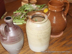 After the salt, cloves, and sliced lemon have been added to the salt glazed crock for the receipt To preserve Asparagus add as much water as vinegar.  The water is in the red ware pitcher and the white wine vinegar in the stoneware.
