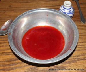After the juice from the mashed strawberries was strained through the sieve for the receipt (recipe) Strawberry Cream put to it a little Orange-flower water.  The orange flower water is in the small blue and white bottle to the right of the basin.